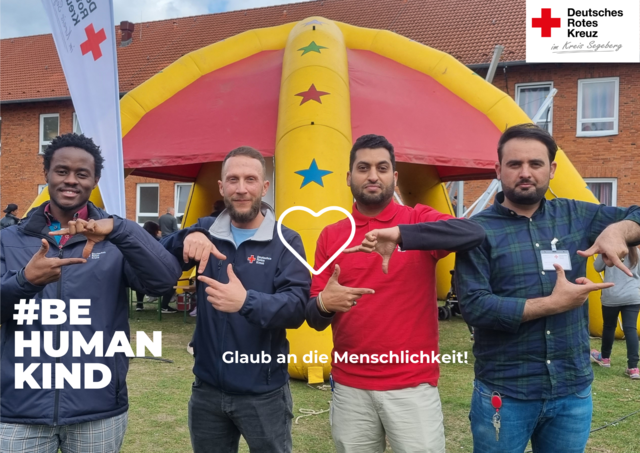 Foto von vier Männern auf einem DRK-Fest. Auf dem Bild steht der Text "Glaub an die Menschlichkeit!" und "#BEHUMANKIND". Zwischen den Männern ist ein weißes Herz gezeichnet.