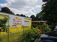 Außenansicht der DRK Kita Schatzinsel. An dem gelben Gebäude befindet sich das Kita Logo.