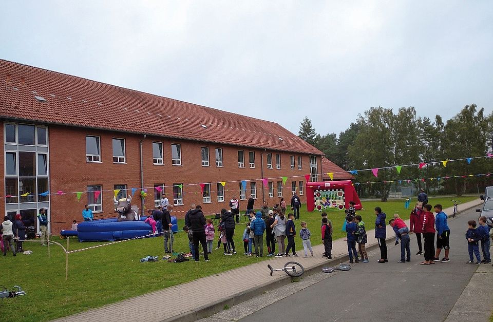 Kinder warten in einer Schlange vor einem Spiel. Sie befinden sich auf einem Fest der DRK Betreuungsdienste Segeberg.