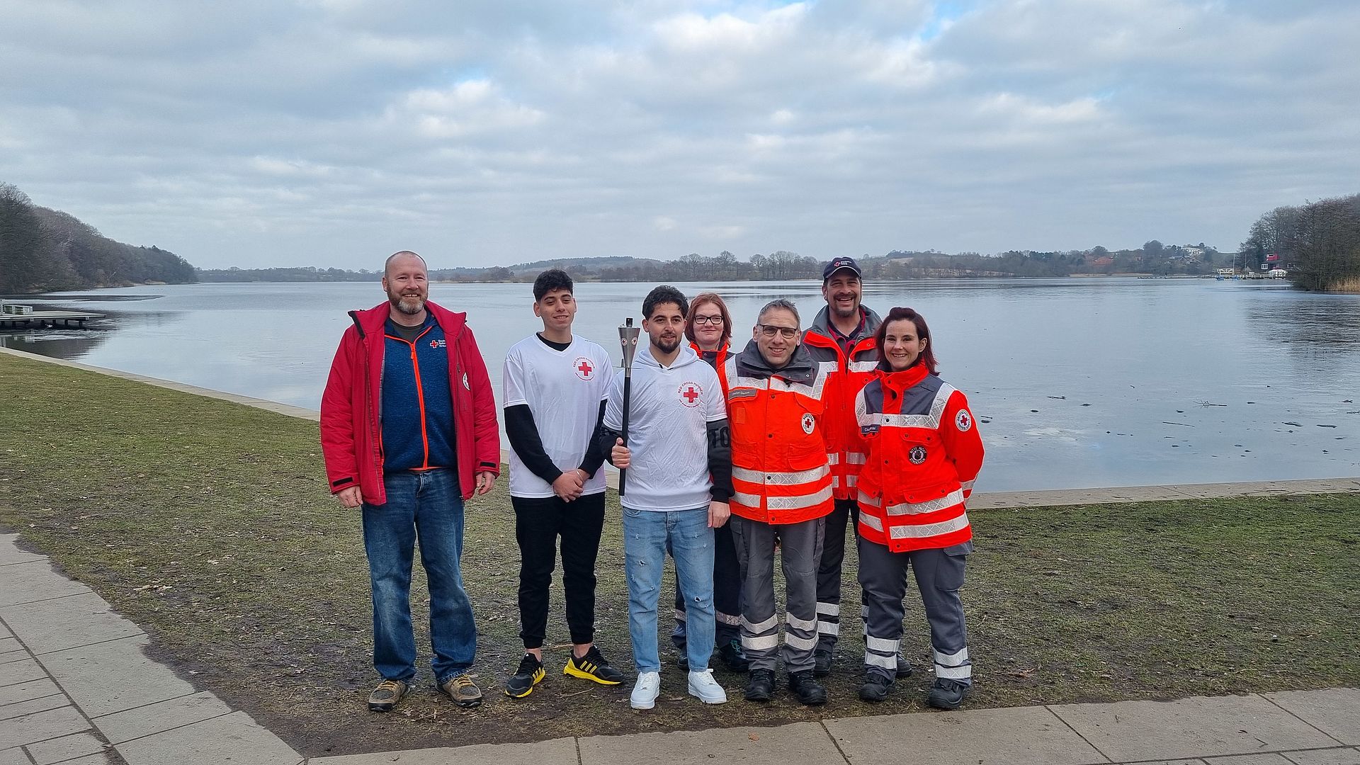Foto vom Fackellauf 2025, mit sieben Menschen die gemeinsam die DRK Fackel halten