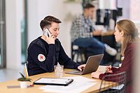 DRK Mitarbeiterin telefoniert in einem Büro.