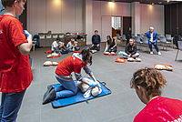 Foto eines Wiederbelebungs-Kurs für Journalisten, angeleitet durch Mitglieder eines Jugendrotkreuz-Schulsanitätsdienstes: Teilnehmende bei der Übung am Dummy.