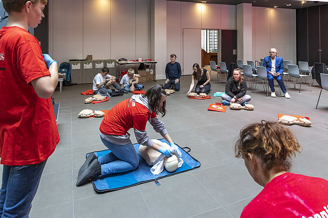 Foto eines Wiederbelebungs-Kurs für Journalisten, angeleitet durch Mitglieder eines Jugendrotkreuz-Schulsanitätsdienstes: Teilnehmende bei der Übung am Dummy.