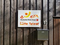 Logo der DRK Kita Lütte Heimat an einer Holzwand.