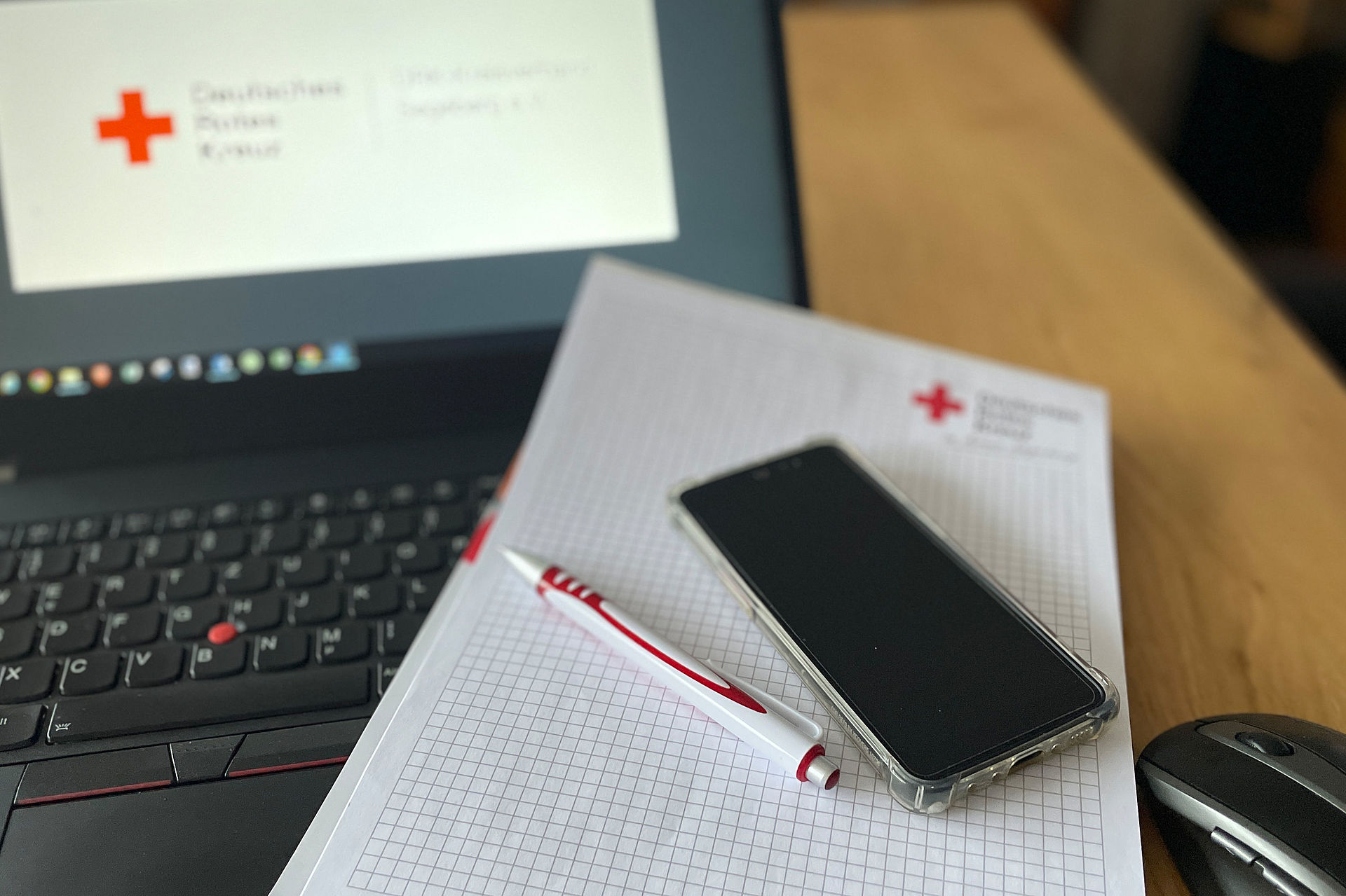 Foto eines DRK Schreibblockes, der auf einem Laptop liegt.