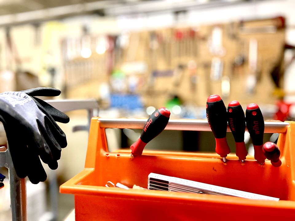 Haustechnik WuP Handwerkskoffer und Handschuhe stehen vor einer Werkbank.