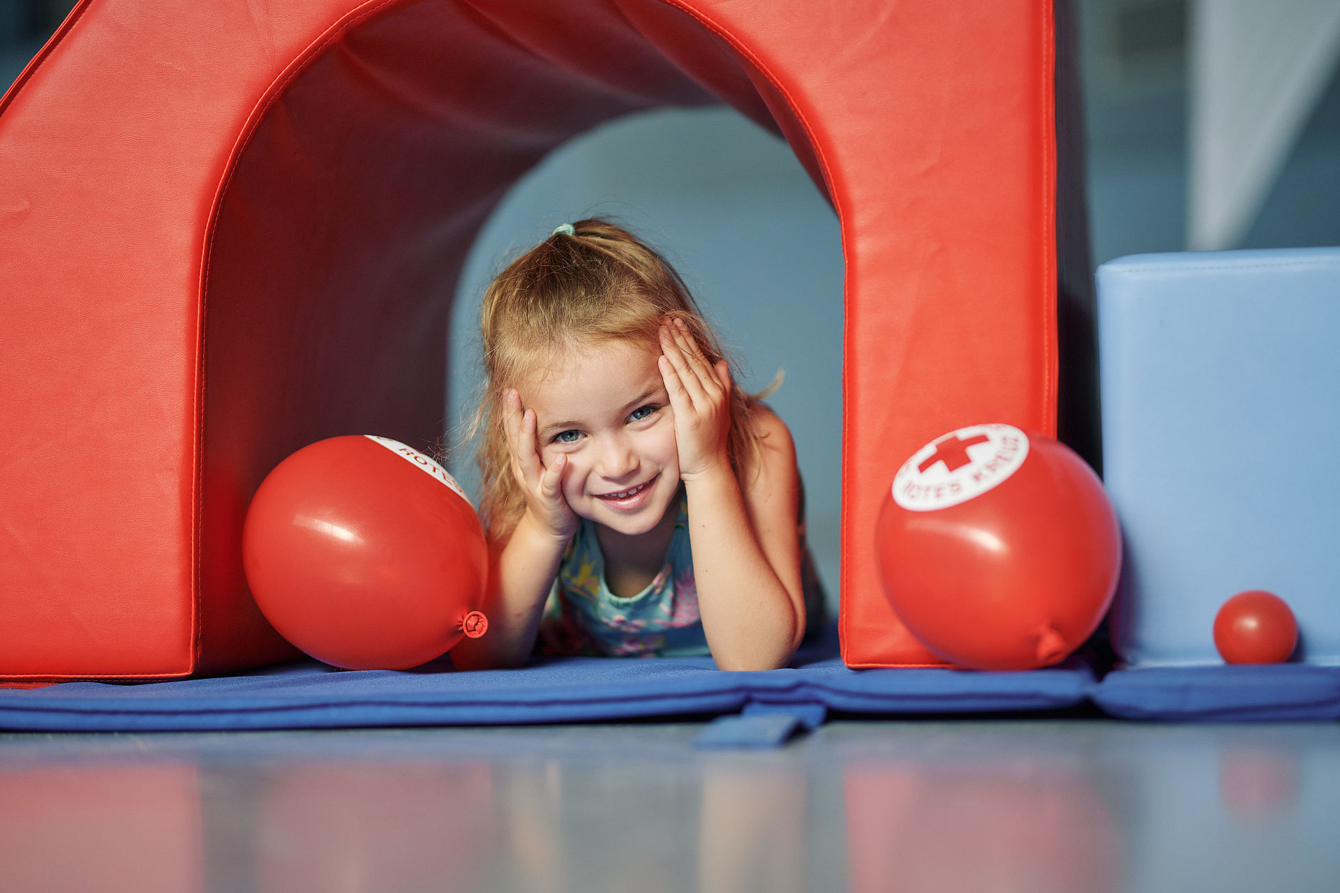 Mädchen liegt unter einem Kletterelement mit Luftballons.